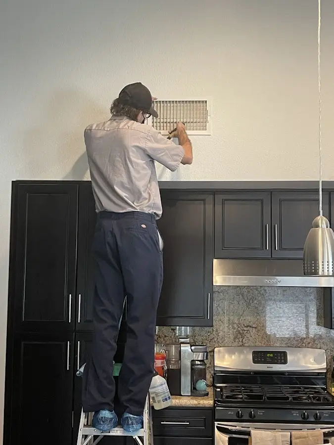 Technician inspecting an air vent during HVAC service in Anoka